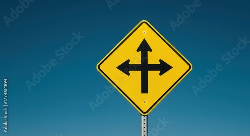 A bright yellow diamond-shaped warning sign indicating a four-way intersection ahead, crucial for traffic safety and driver awareness on the highway system, street, caution, road