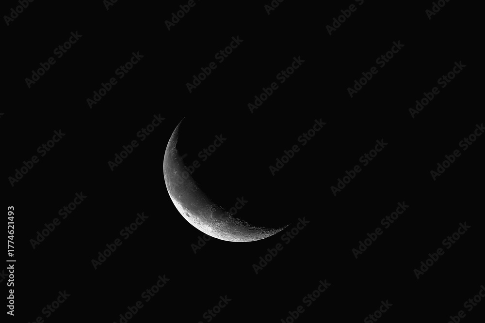 Fototapeta premium A sliver of the crescent moon glowing in the pitch black night sky.