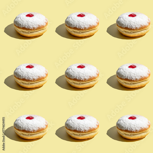 Seamless pattern of powdered donuts with cherry on yellow background