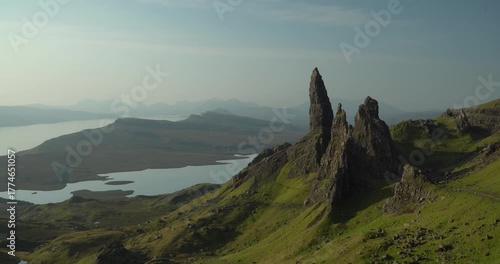 The Old Man of Storr on the Isle of Skye in Scotland, with natural light, dominating the hill going to the ocean, with a lake inbetween