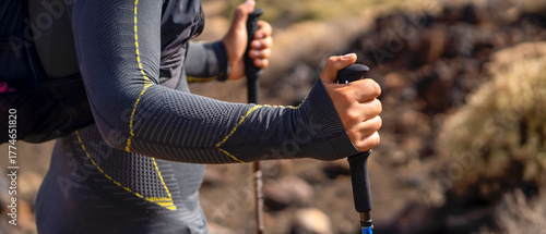 A man is hiking, running with trekking poles in the mountains.