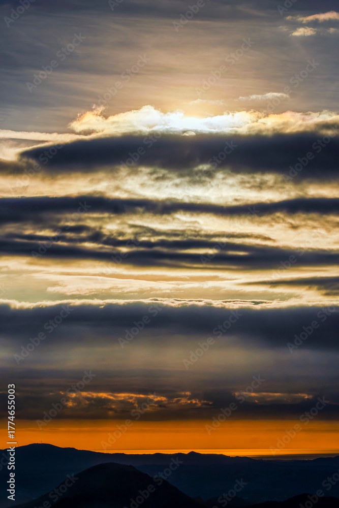 Obraz premium Beautiful landscape with mountains among fog and clouds at sunset.