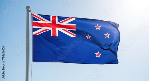 A flag of New Zealand with a blue field and red and white stars against a clear blue sky