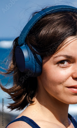 A girl with a wireless headphones, is listening music outdoors.