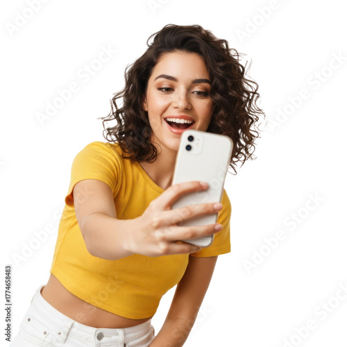 A cheerful young woman in a yellow top taking a selfie with a white smartphone.