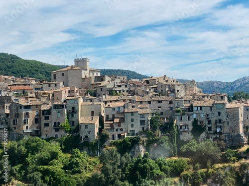 Scenic view of the medieval village of Tourrettes-sur-Loup on the French Riviera, nestled among green hills on a sunny summer day. Stone houses, lush landscape and bright Mediterranean atmosphere.