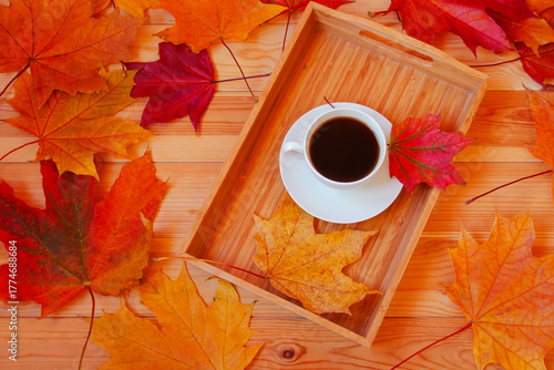 Cup of coffee and colorful autumn leaves on wooden table. Top view.