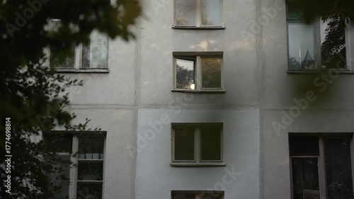 View through the branches of the facade and windows of a Soviet-type residential building