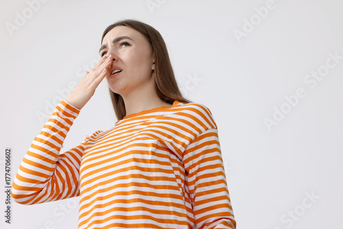 Photos Young woman suffering from bad smell and covering her nose indoors, low angle view