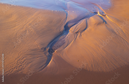 Beautiful ornamental sand patterns made by flowing water on the beach of Baltic Sea. Sunny summer day in Latvia.