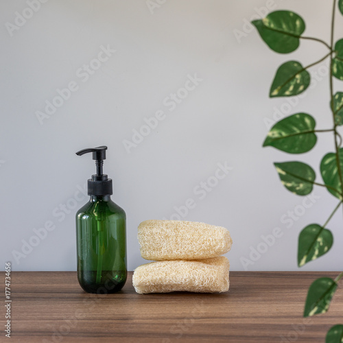 Natural Spa Products with Green Pump Bottle and Loofah Sponges on Wooden Table
