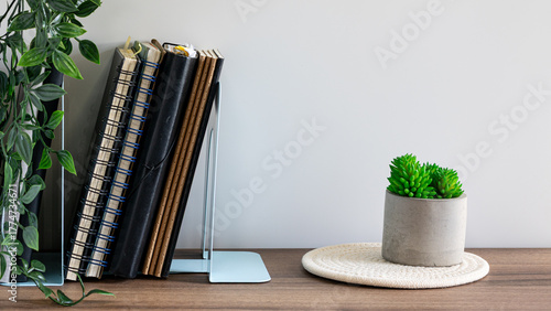 Minimalist Workspace with Notebooks and Green Plant on Wooden Desk