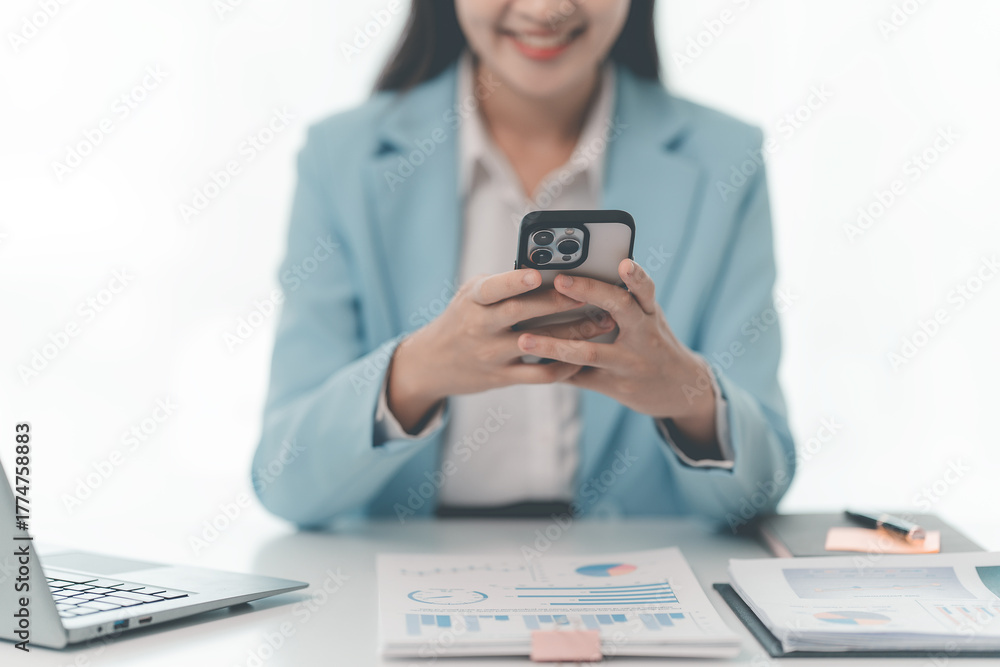Fototapeta premium Asian businesswoman working with documents and computer at desk in office. Female office worker holding pen and using calculator while reading documents on desk.