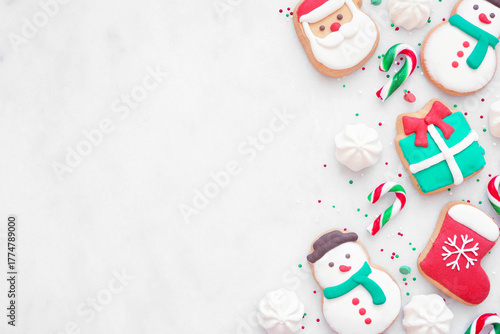 Colorful Christmas sweets side border on a white marble background with copy space. Overhead view. Holiday baking concept.