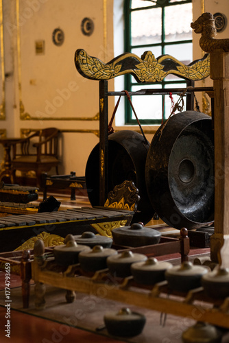 Traditional Indonesian gamelan ensemble with gongs and metallophones in ornate hall.