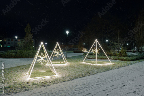 Minimalist Illuminated Christmas Pyramids with Snowflakes in Park on Dark Winter Night