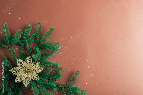Fir branches and golden flower ornament on brown background. Christmas concept. Top view, flat lay, copy space