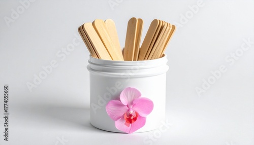 A white ceramic container holds a bundle of light brown wooden craft sticks with rounded edges