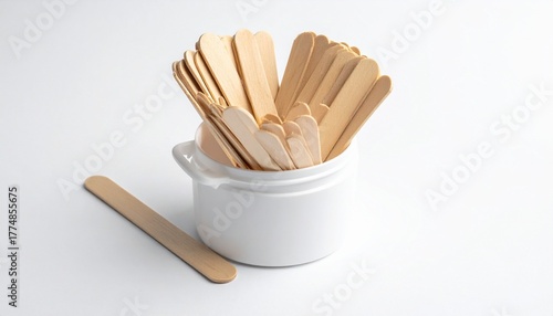 A white ceramic container holds a bundle of light brown wooden craft sticks with rounded edges