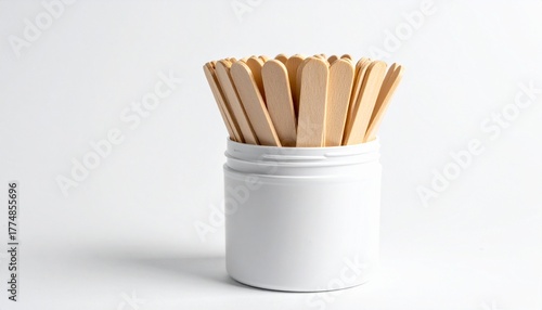 A white ceramic container holds a bundle of light brown wooden craft sticks with rounded edges