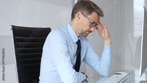 Bilde på lerret Businessman sitting at a desk in his office, suffering from a severe headache an