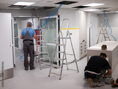 Cuadro en lienzo An electrician runs cables over a suspended ceiling in a new room