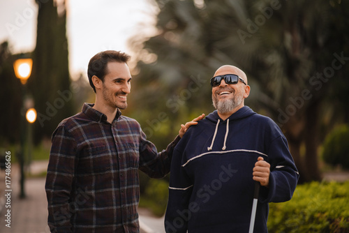 Bild auf Leinwand Blind Man and His Young Helper Laughing Together in the Park
