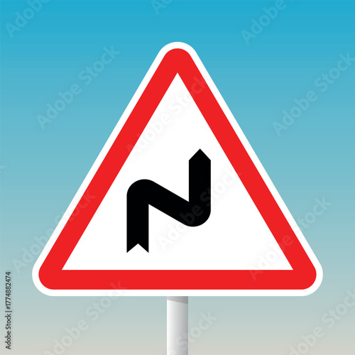 Double bend road warning sign with red triangle and pole for traffic safety and hazard alerts