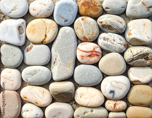 Array of smooth, round, natural stones in various colors and patterns on rough background