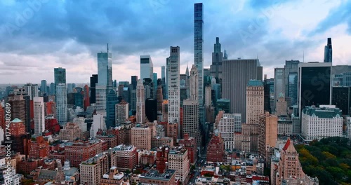 Multi-storied buildings and skyscrapers of amazing New York, USA. Approaching the beautiful greenery of Central Park. Dramatic cloudscape covering the sky over the city.