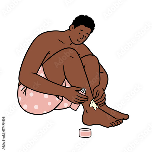 Young black man applying cream to his leg while sitting cross-legged  