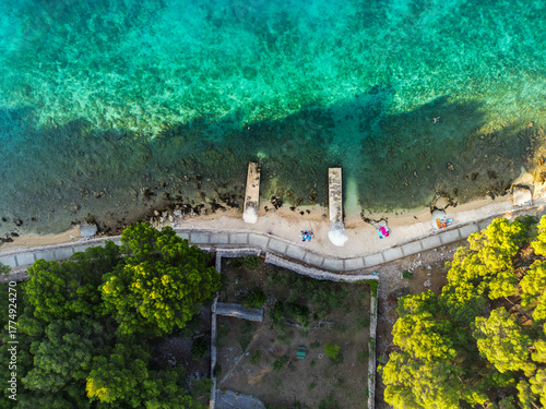 Top down aerial view of beautiful, secluded beach in the small bay of Cres island, Croatia, with beatiful, turquoise sea splashing the sand shore