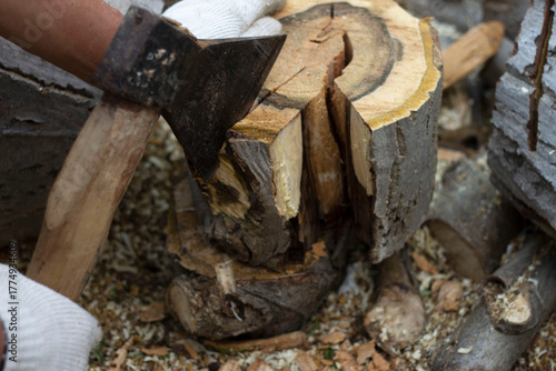 Men's hands hold an axe. They are preparing firewood for the winter