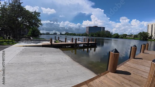 A scenic view of a calm river from the shore, featuring a small wooden pier extending over the water.