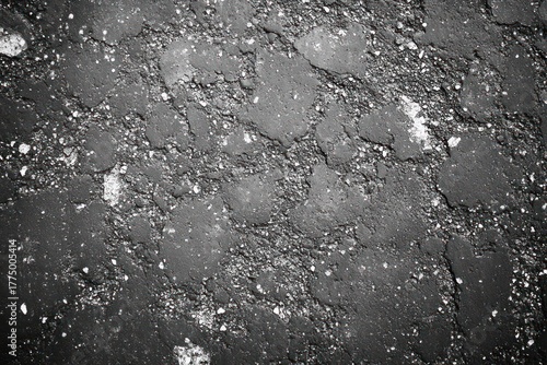 Fototapeta Naklejka Na Ścianę i Meble -  Close-up view of cracked and rough asphalt pavement with scattered small stones and debris in black and white