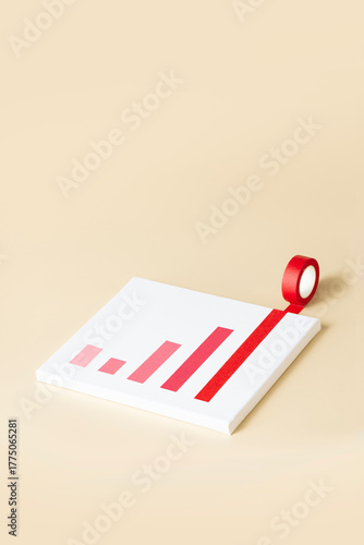 Conceptual success graph still life on cream colour background. One red tape rolling out from a white canvas background.