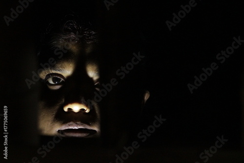 Artistic woman’s face lit in darkness, expressing resilience, life, and emotion through shadow and subtle human expression.