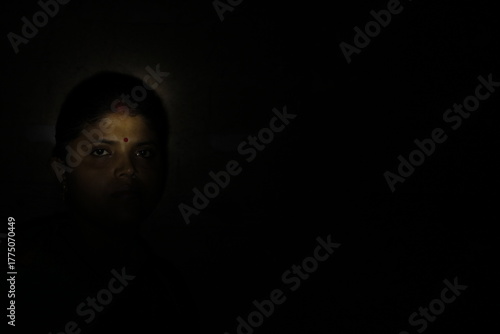 Artistic woman’s face lit in darkness, expressing resilience, life, and emotion through shadow and subtle human expression.