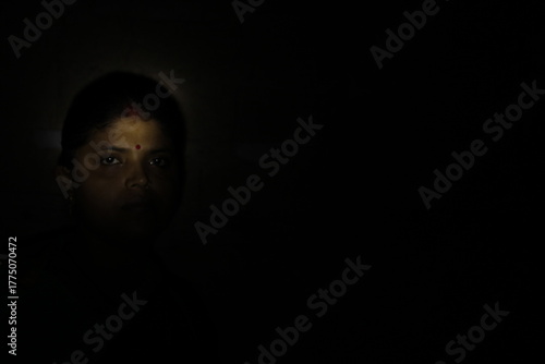 Dramatic low-light photograph of an Indian woman wearing a traditional saree, reflecting dignity, calmness, and emotional depth through expressive lighting.