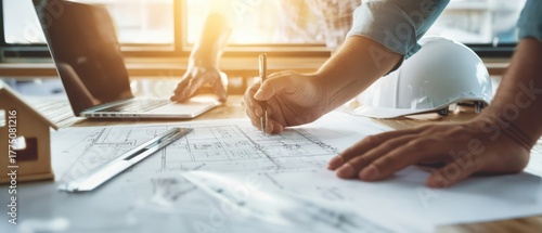 The Architect Drawing Construction Blueprints on Office Desk with Helmet and Laptop
