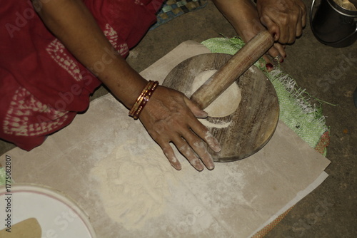 Close-up of an Indian woman’s hands rolling dough on a wooden board to make chapatis, symbolizing tradition, love, and the essence of home-cooked food in Indian households.