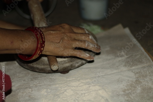 Close-up of an Indian woman’s hands rolling dough on a wooden board to make chapatis, symbolizing tradition, love, and the essence of home-cooked food in Indian households.