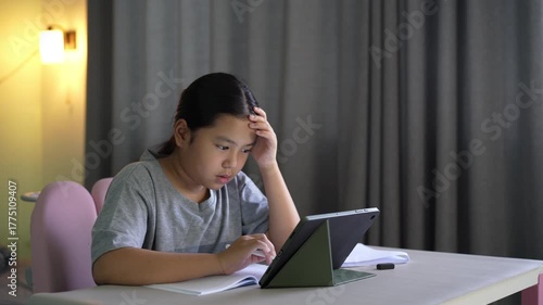 asian child study online class to stress learning writing on computer tablet and book or kid girl student headache studying write or people learn from home school by video call technology education