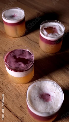 Elegant layered alcoholic drink, Violet swirl atop creamy foam, Decorative cocktail with citrus and syrup details, Artistic beverage showcasing syrup cascade over whipped garnish