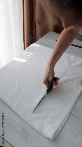 Fabric cutting scene, Seamstress measures cloth carefully, Clean workspace with precise fabric trimming, Caucasian seamstress carefully trims fabric on clean workspace