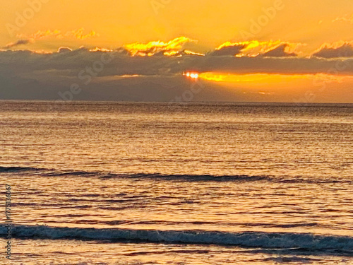 Intense Golden Sunset Over the Ocean Horizon with Sunburst Through Clouds and Dramatic Rays