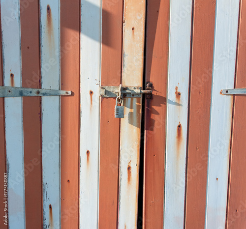 padlocked wooden door with white and red stripes