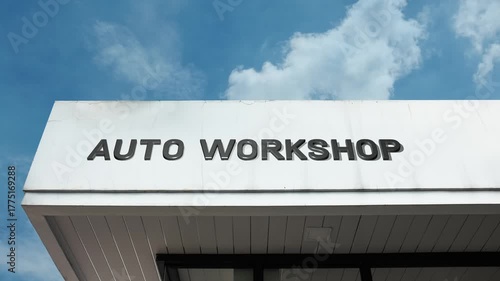 Auto Workshop word sign displayed on the exterior of a modern building under a clear blue sky, symbolizing vehicle maintenance, mechanical services, car repair, and automotive operations