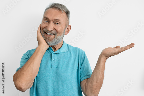 Senior man radiates happiness while easing his toothache, and points to an empty space with his hand. Concepts of dental health in elderly