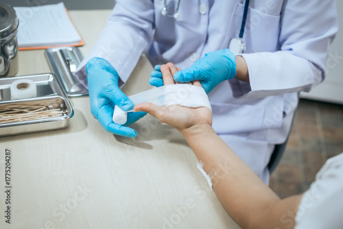 A male doctor wearing a white coat and blue medical gloves carefully bandages a patient’s arm, showing professionalism, hygiene, and compassion during wound treatment in a modern healthcare clinic